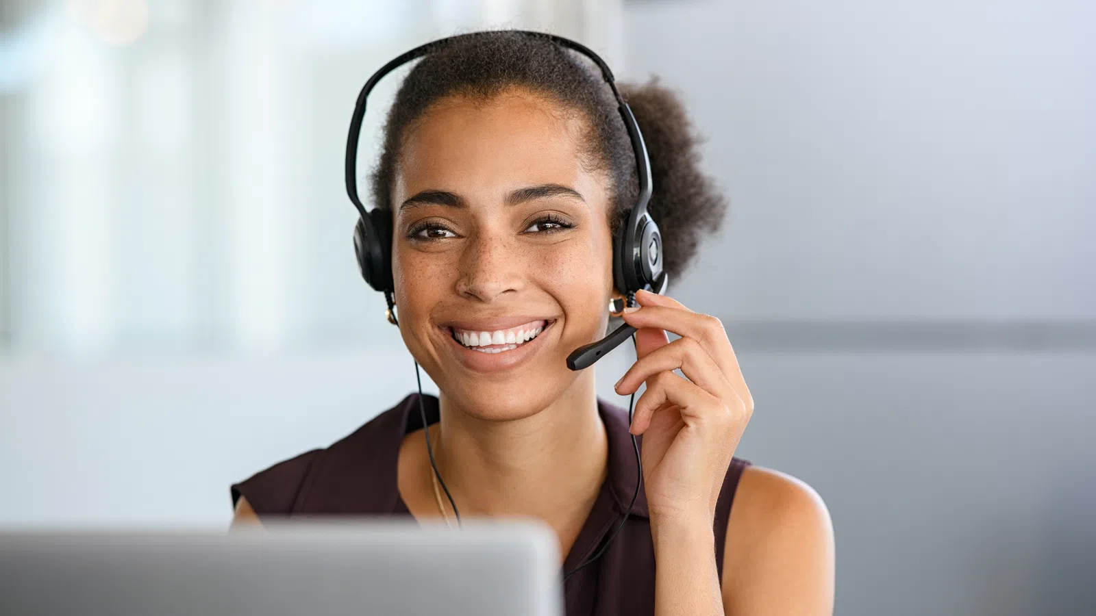Smiling woman in headset with laptop, representing customer support and remote work.