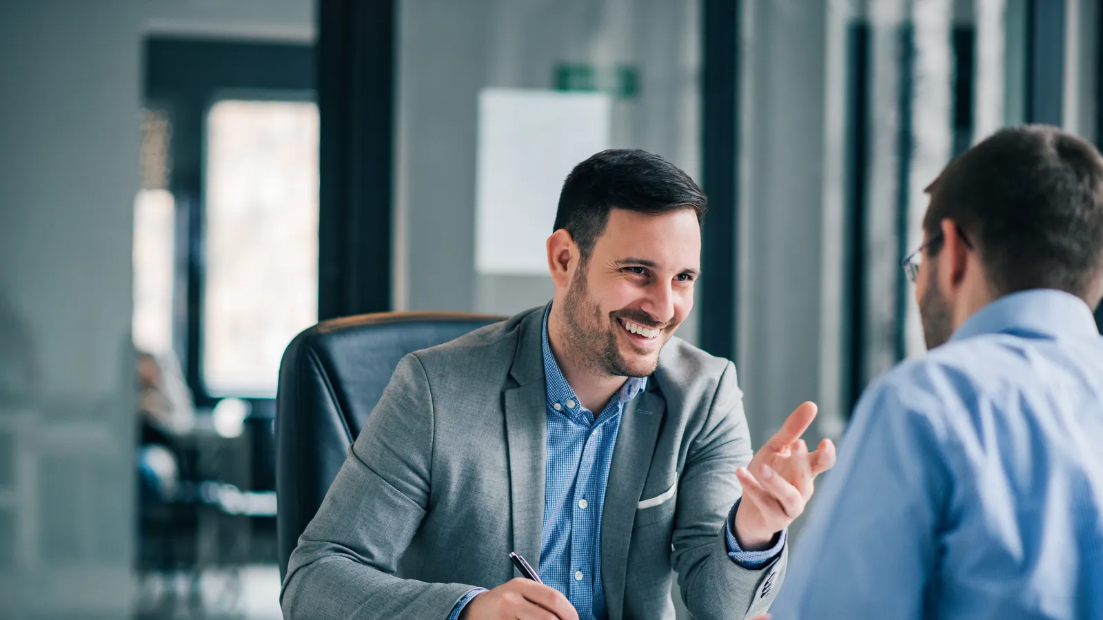 a man smiling and talking to another man