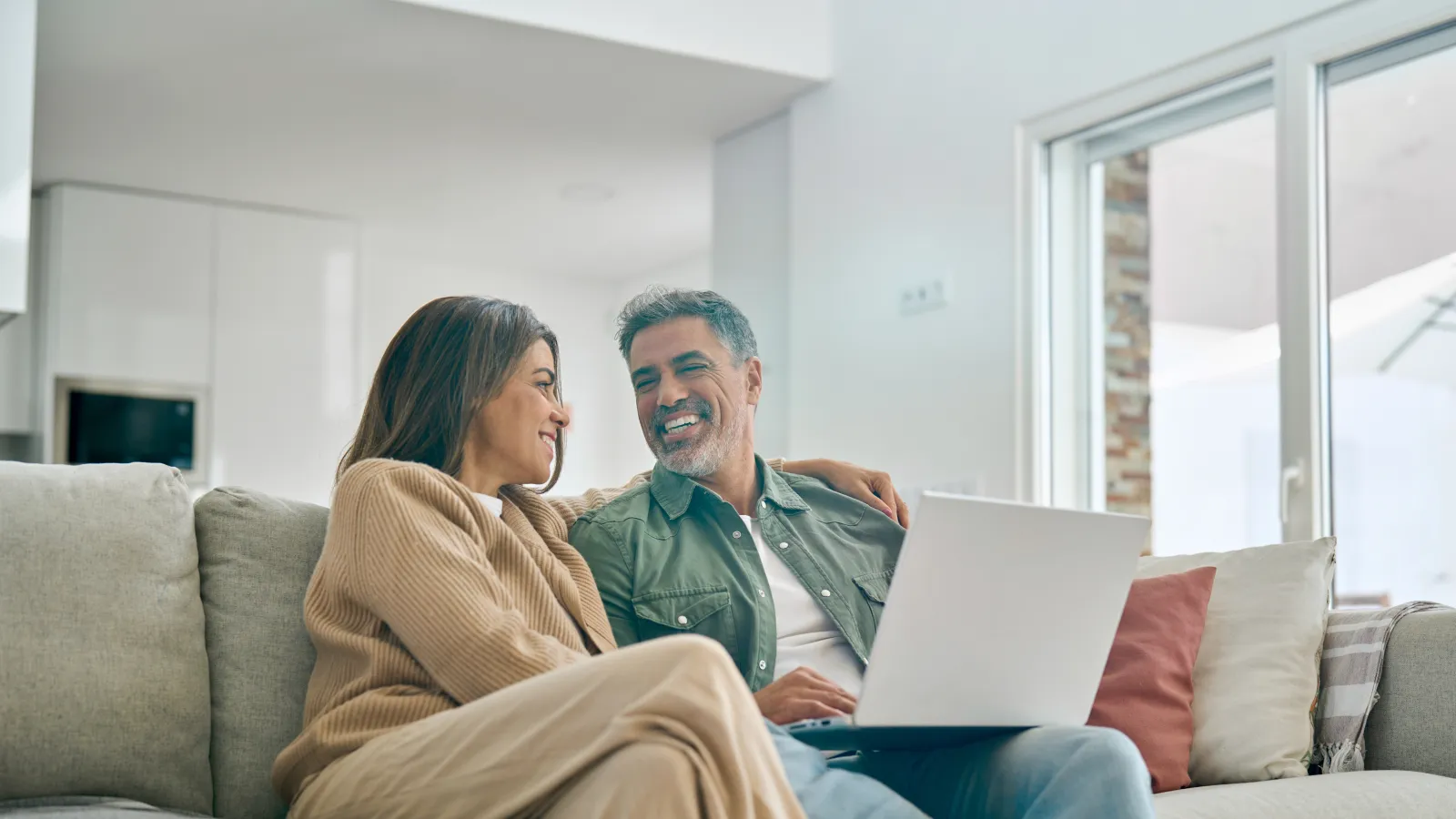 a man and woman sitting on a couch with a laptop