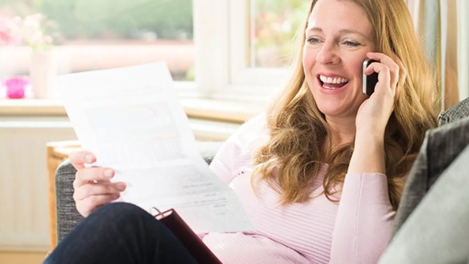 a woman sitting on a couch looking a paper