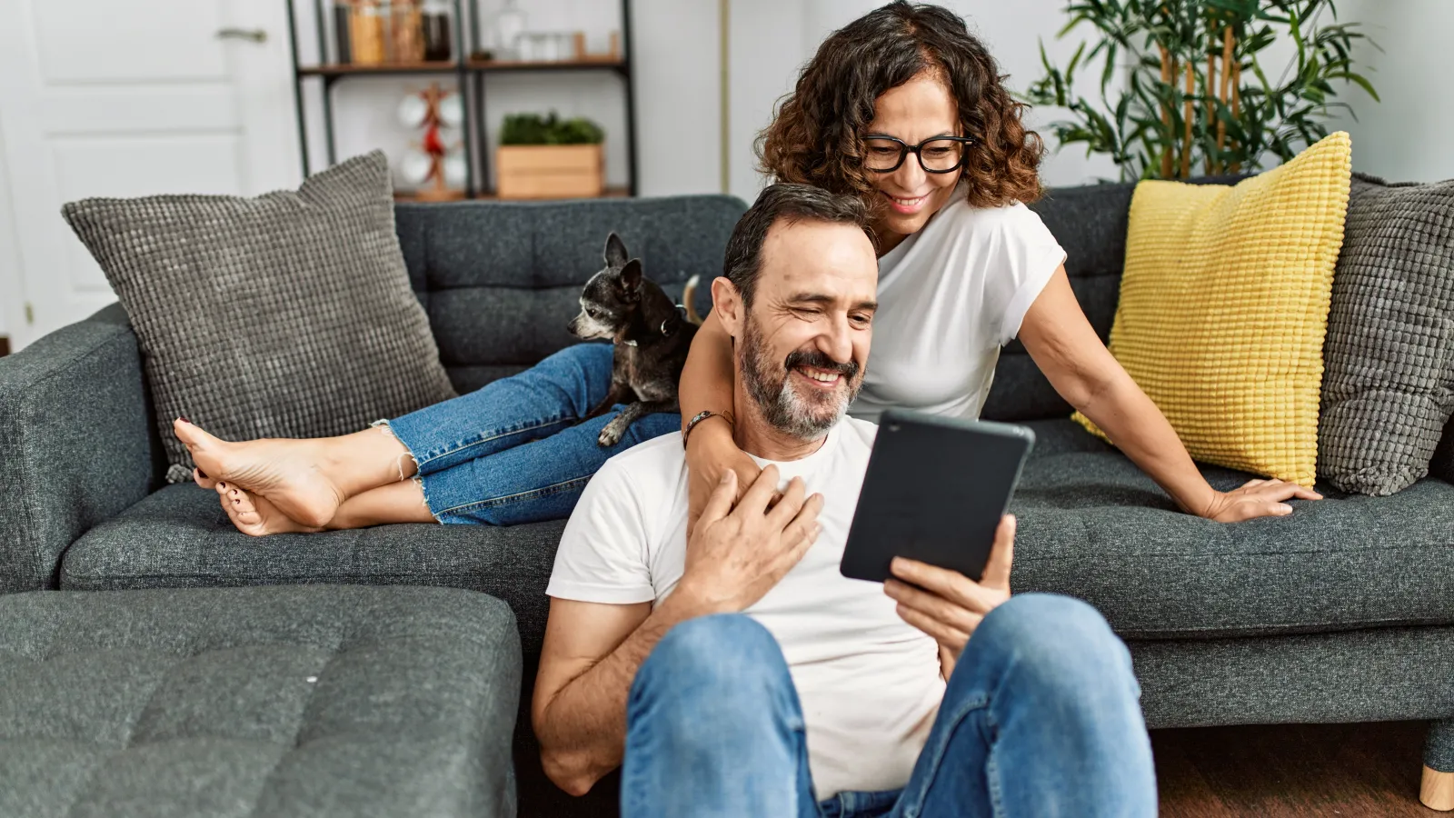 a man and a woman with their pet looking at a tablet