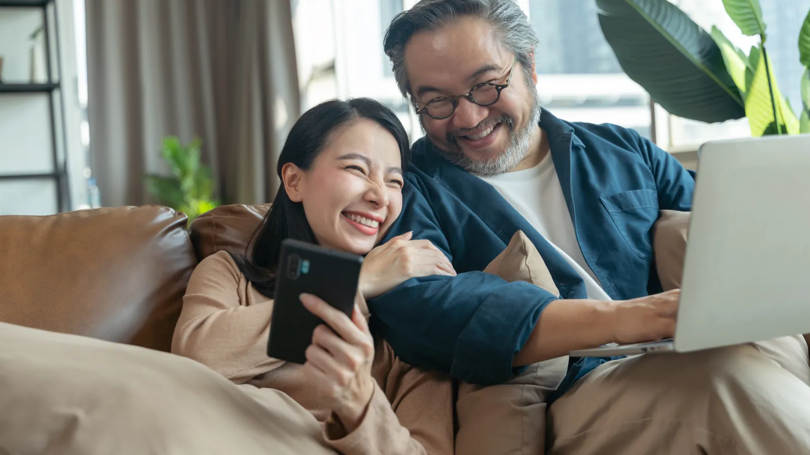 a man and a woman sitting on a couch looking at a computer