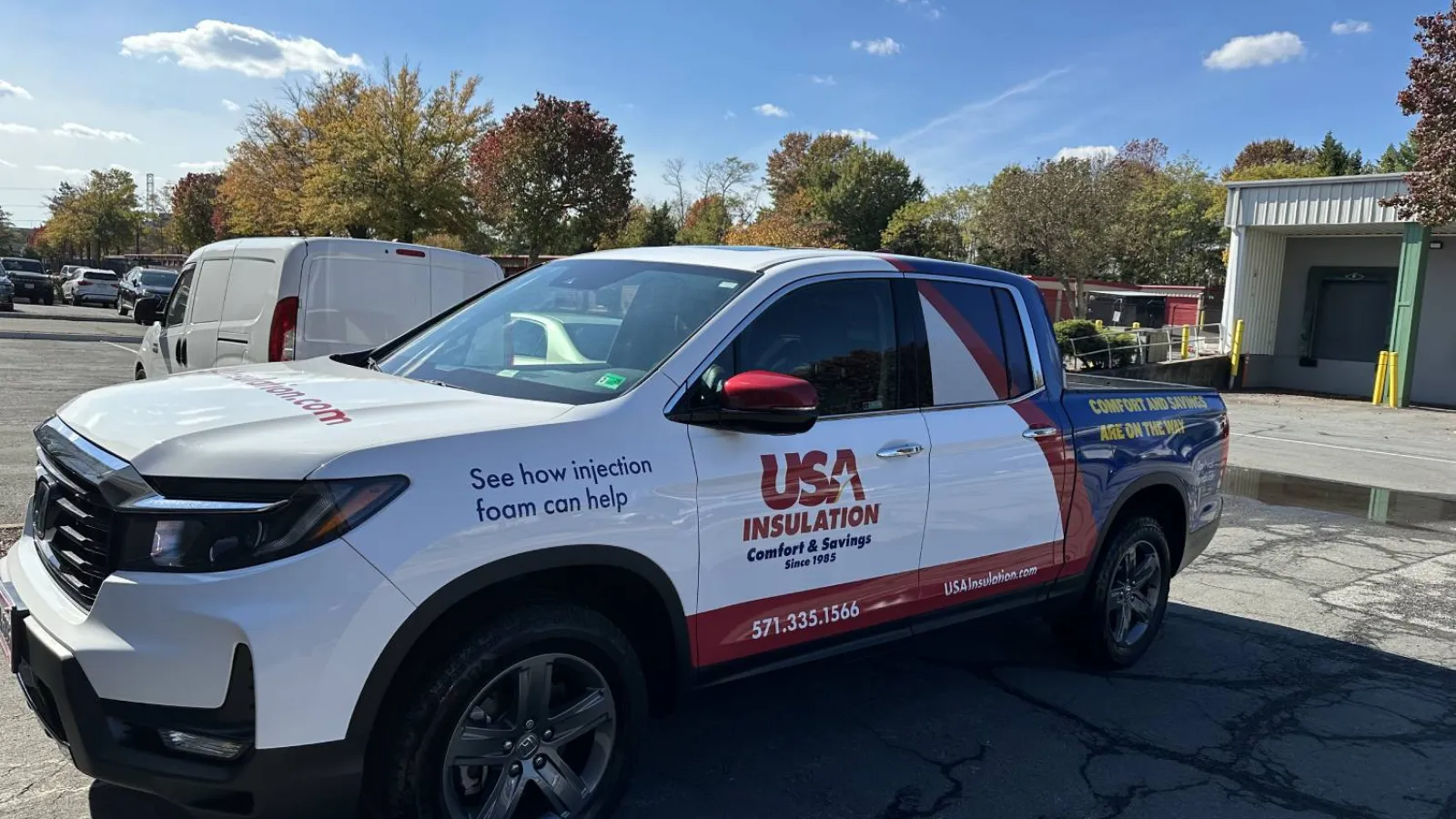 White pickup truck with USA Insulation branding parked in a lot on a sunny day with fall foliage.