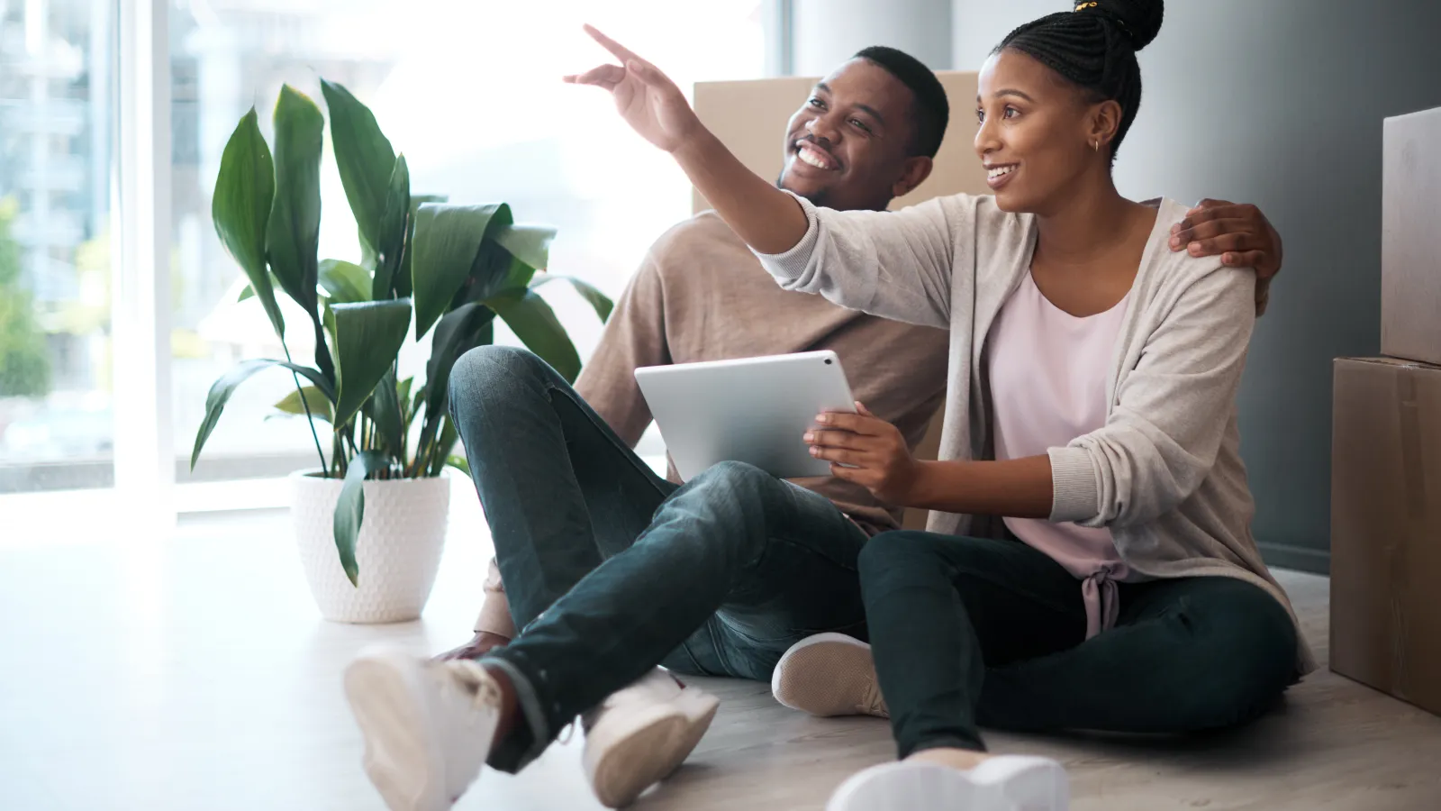 a man and a woman sitting on the ground holding a tablet