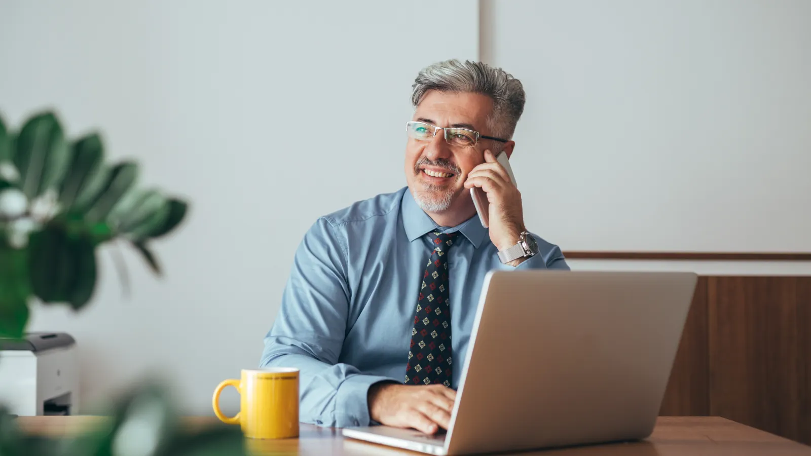 a man on his phone at a table with a laptop