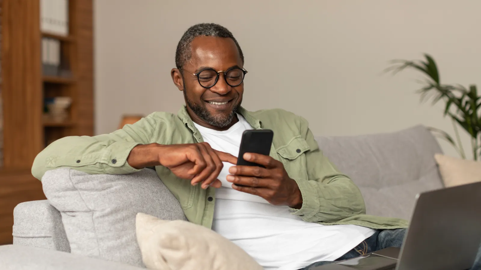 a man sitting on a couch and looking at his phone