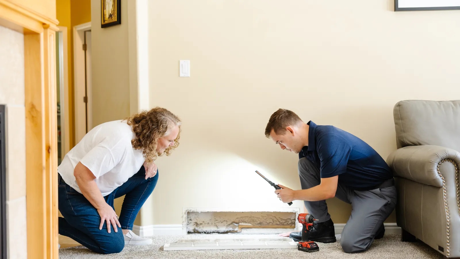 a Zerorez male technician and a woman looking inside a dirty air return vent