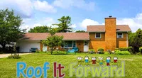 Brick suburban house with green lawn, trees, and colorful Roof It Forward text and cartoon children on the grass