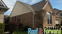 Side view of a brick house with a steep roof under a clear blue sky and landscaped yard