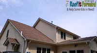 Beige house with brown roof under blue sky featuring Roof It Forward charity logo urging help for kids.