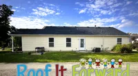 Single-story beige house under a blue sky with text Roof It Forward and cartoon children at the bottom.