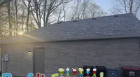 Sunset behind a gray brick building with a roof, trash bins, and colorful Roof It Forward text with cartoon kids.