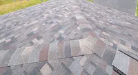 Newly installed asphalt shingle roof viewed from above on a suburban house with driveway and lawn