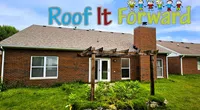 Brick house with a gray roof, wooden pergola, and garden under a blue sky with Roof It Forward logo and cartoon kids.