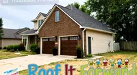 Suburban house with new roof, double garage, and Lawn sign for Roof It Forward roofing service.