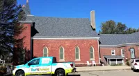 a Roof It Forward truck parked next to a church