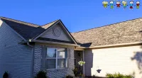 Single-story house exterior with brick and siding under a clear blue sky with Roof It Forward logo.