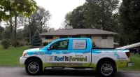 a Roof It Forward truck parked in front of a home