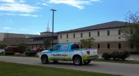 a Roof It Forward truck parked in front of a church building