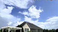 House with dark roof and large lawn under bright blue sky with white pergola swing and cartoon Roof It Forward logo