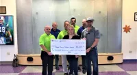 Roof It Forward employees holding a large check