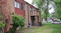 a large brick building with grass in front of a house