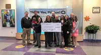 Roof It Forward employees holding a large check