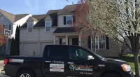a Roof It Forward truck parked in front of a house