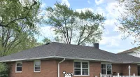 a house with trees in front of a brick building