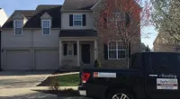 a Roof It Forward truck parked in front of a house