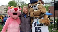 a girl posing with two mascots