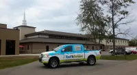 a Roof It Forward truck parked in front of a church