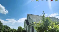 Suburban house with new roof under bright blue sky and Roof It Forward logo with children cartoon above.