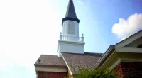 a small clock tower in front of a brick building