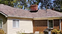 a house with a chimney and a couple of people in front of it