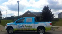 a Roof It Forward truck parked in front of a house