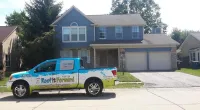 a Roof It Forward truck parked in front of a house