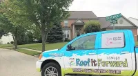 a Roof It Forward truck parked in front of a house