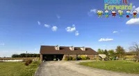 Rural brick house with brown roof under blue sky and green lawn in peaceful countryside setting