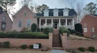 a large brick building with grass in front of a house