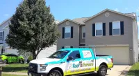 a Roof It Forward truck parked in front of a house