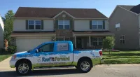 a Roof It Forward truck parked in front of a house
