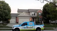 a Roof It Forward truck parked in front of a house