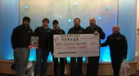 Roof It Forward employees holding a large check