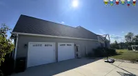 Bright sunny day showing a house with a double garage, basketball hoop, and clear blue sky.