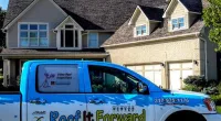 a Roof It Forward truck parked in front of a house