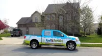 a Roof It Forward truck parked in front of a home