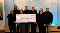 Roof It Forward employees holding a large check