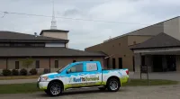 a Roof It Forward truck parked in front of a church