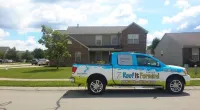 a Roof It Forward truck parked in front of a house
